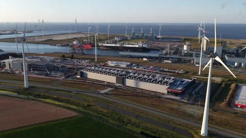 Wind turbines generating clean energy around industrial port Stock Footage 344768304