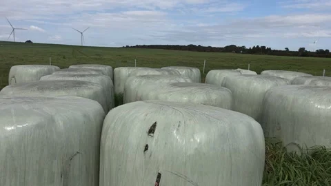 Wind turbines generating clean energy over hay bales Stock Footage 345233727