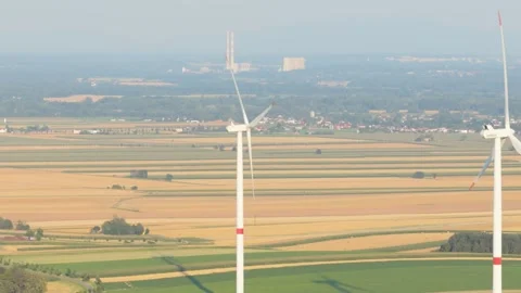 Wind turbines generating clean energy over agricultural fields Stock Footage 348132887
