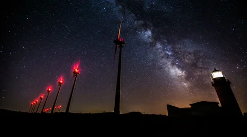 Wind turbines generating clean power with lighthouse on the milky way Stock Footage 33801833