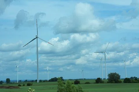 Wind turbines generating electricity installed on an agricultural green field Stock Photos