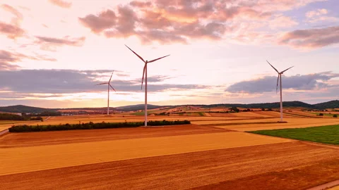 Wind turbines generating power in golden fields at dusk. High angle view of Stock Footage 339015034