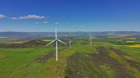 Wind turbines on hills under blue sky during daytime in rural area Stock Footage 338275367