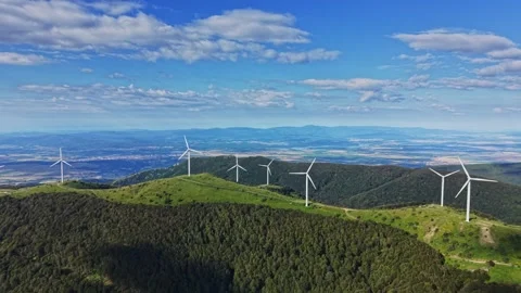 Wind turbines on a hillside with a blue sky and distant mountains 库存影片 339161676