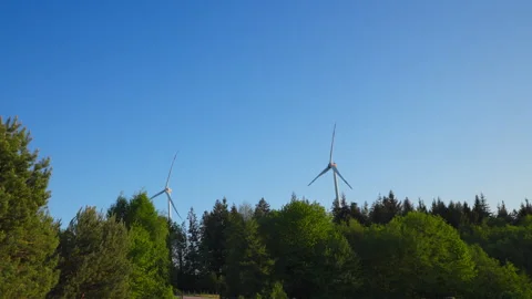Wind Turbines in Motion over a Lush Green Forest Landscape on a Sunny Day 動画素材 338349987