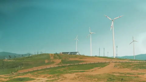 Wind turbines on a mountain pass, renewable energy. Clouds are floating, a hazy  Stock Footage 221612760