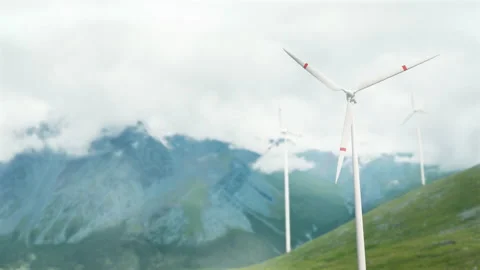 Wind turbines on a mountain pass, renewable energy. Clouds are floating, a hazy  Video stock 222700929