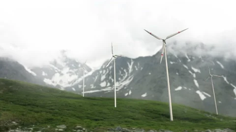 Wind turbines on a mountain pass, renewable energy. Clouds are floating, a hazy  Video stock 222701379