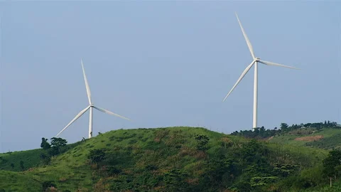 Wind turbines on a mountain top surrounded by green trees Stock Footage 188540348