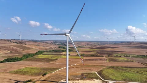 Wind turbines on open fields with a clear blue sky Stock Footage 303207824