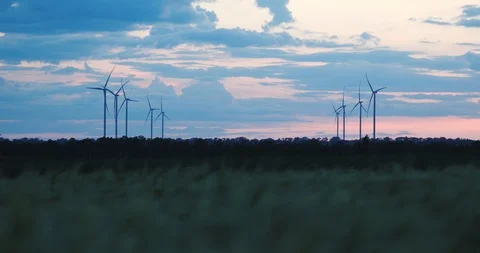 Wind turbines operate in spring field against cloudy sky Stock Footage 113602127