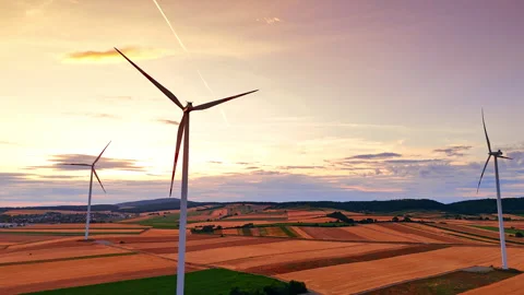 Wind turbines over agricultural fields during vibrant sunset. Aerial view of Stock Footage 339017485
