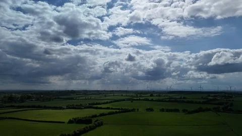 Wind Turbines Over Green Fields Under Dramatic Cloudy Sky Stock Photos