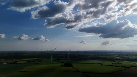 Wind Turbines Over Green Fields Under Cloudy Sky Stock Photos