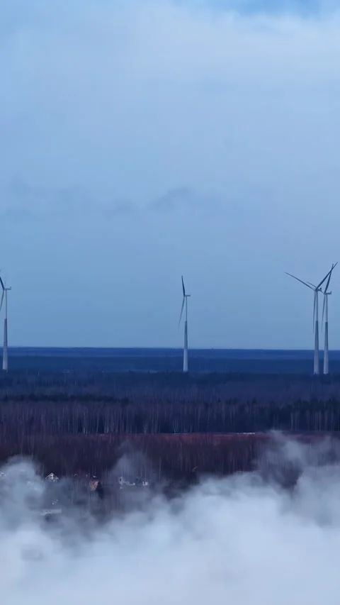 Wind turbines producing renewable energy on a cold and foggy morning from an Stock Footage 336242714