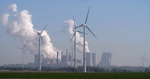 Wind turbines producing sustainable energy in front of lignite fired power plant Stock Footage