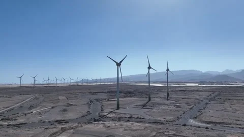 Wind Turbines on Raw Field Under Clear Blue Sky, Drone Stock Footage 310017835