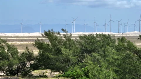 Wind turbines revealed by smooth sideways telephoto 7x drone move over coastal Stock Footage 328500262