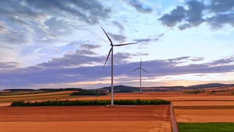 Wind turbines rising above patterned agricultural fields at dusk Stockbeeldmateriaal 339744990