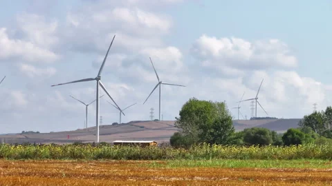 Wind turbines on rolling fields under cloudy skies Stock Footage 303266651