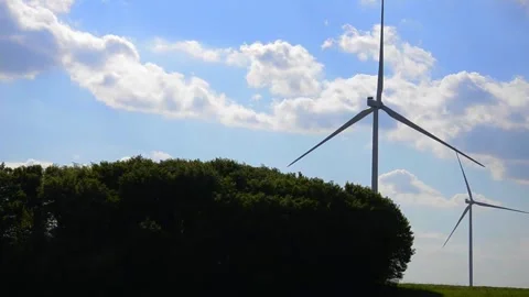 Wind turbines rotating in a green field under blue sky 스톡 동영상 339094847