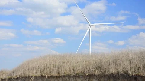 Wind turbines rotating in a green field under blue sky 스톡 동영상 339094848