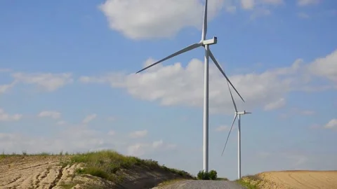 Wind turbines rotating in a green field under blue sky 스톡 동영상 339094849