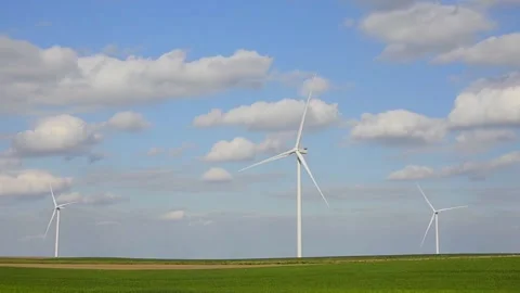 Wind turbines rotating in a green field under blue sky 스톡 동영상 339094850
