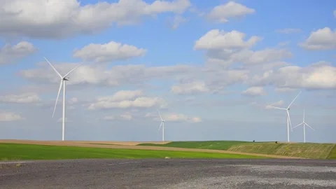 Wind turbines rotating in a green field under blue sky 스톡 동영상 339094857