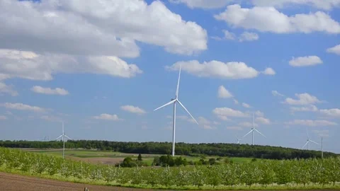 Wind turbines rotating in a green field under blue sky 스톡 동영상 339094858