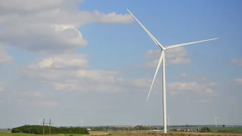 Wind turbines rotating in a green field under blue sky 스톡 동영상 339094871