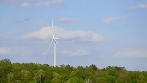 Wind turbines rotating in a green field under blue sky 스톡 동영상 339094873
