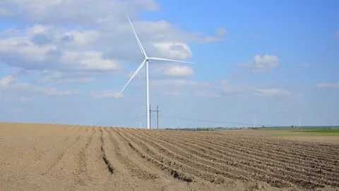 Wind turbines rotating in a green field under blue sky 스톡 동영상 339094874