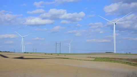 Wind turbines rotating in a green field under blue sky 스톡 동영상 339094883