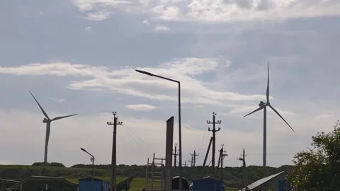 Wind turbines rotating under cloudy sky near power lines Vidéo 315358536