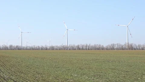 Wind turbines spin energetically against a blue sky, harnessing renewable energy Stock Footage 304462996