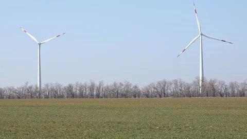Wind turbines spin energetically against a blue sky, harnessing renewable energy Stock Footage 304463003