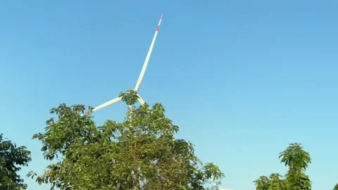 Wind turbines spin on open land seen from a vehicle in motion while traveling Stock Footage 332029702