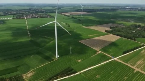 Wind turbines spin in vast green fields under a cloudy sky. Video stock 336334494
