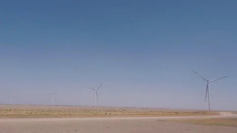 Wind turbines spinning on dry flat land Vídeos de archivo 347379749