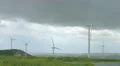 Wind turbines spinning in green field under gray stormy sky, bad rainy weather 4k or 4k+ Resolution