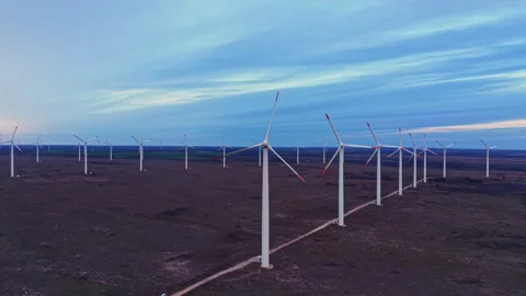 Wind turbines stand aligned in a field during the twilight hours showcasing Video stock 331895903
