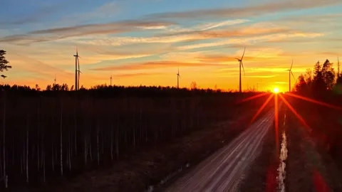 Wind Turbines Stand Along a Quiet Road as the Sun Sets, Creating a Peaceful Видео 336241671