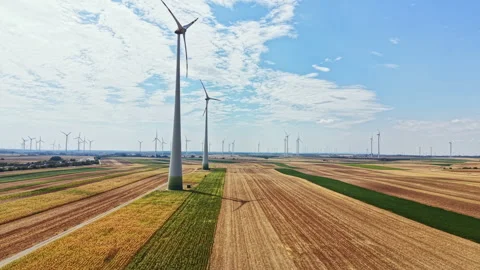 Wind turbines stand among fields in a rural area during a sunny day with some Stock Footage 342726142