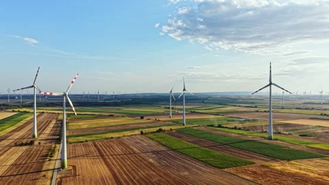 Wind turbines stand in a field during daylight with clear skies and clouds Stock Footage 344161985