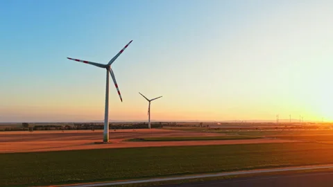 Wind turbines stand in a field during sunset in a rural area with clear skies Stock Footage 344264955