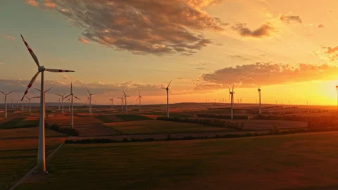 Wind turbines stand in a field at sunset with a colorful sky in the background Stock Footage 344128167