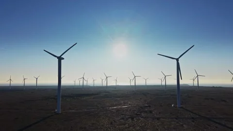 Wind turbines stand in a field under the sun during the day 스톡 동영상 336541705
