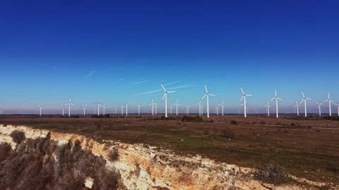 Wind turbines stand in a field under clear blue sky during the day Stockbeeldmateriaal 336542113