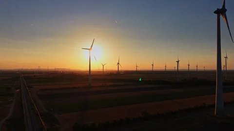Wind turbines stand in fields during sunset in an open area Stock Footage 342609367